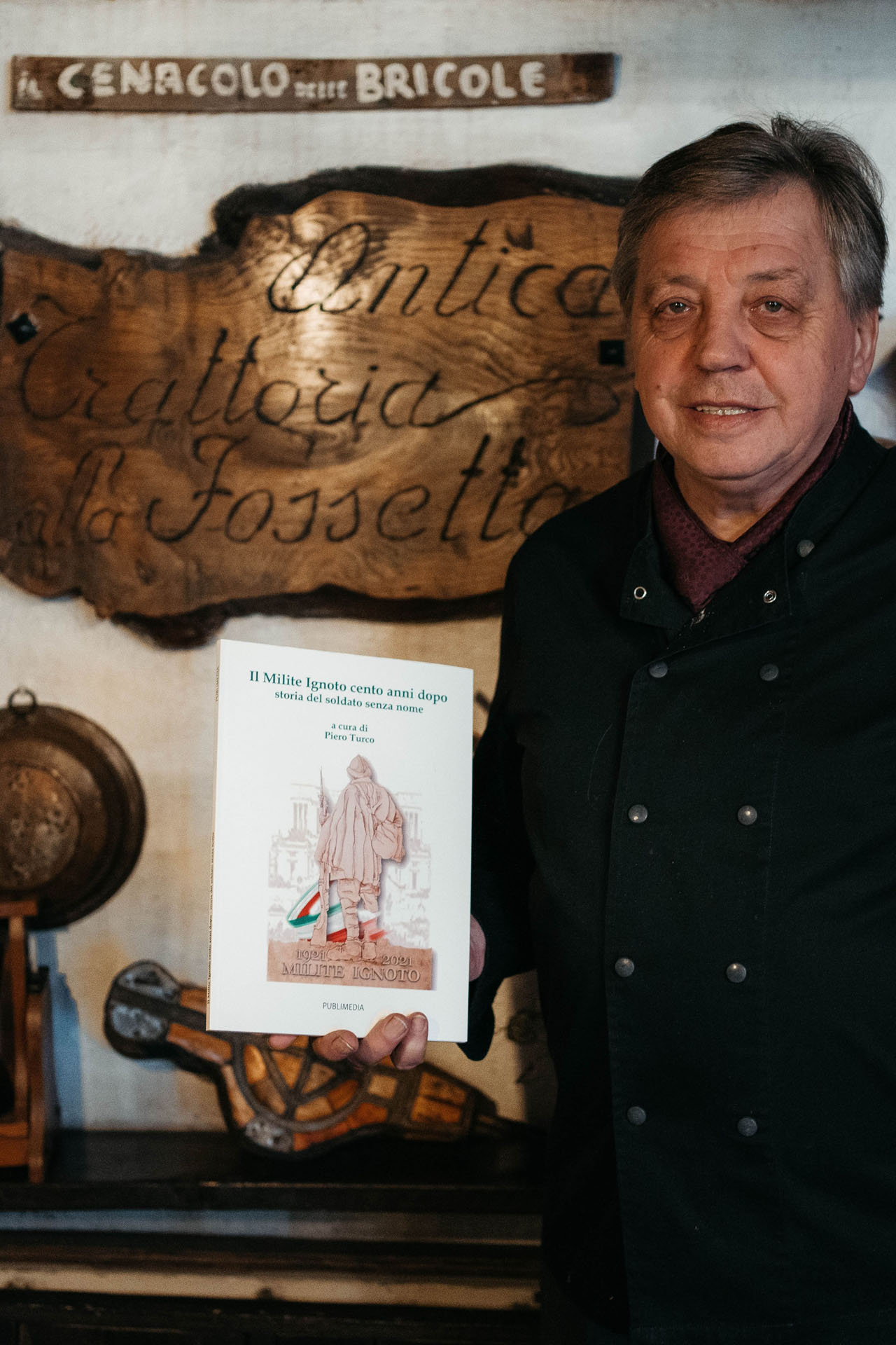 Flavio Doretto mostra un libro presentato in occasione di un evento del Cenacolo delle Bricole, associazione culturale che si riunisce presso la trattoria.